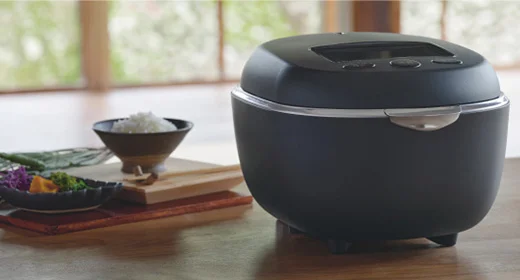 和室の木のテーブルに置かれた、墨黒のタイガー 土鍋圧力IHジャー炊飯器 JRT-A100と茶碗に盛られたごはん
