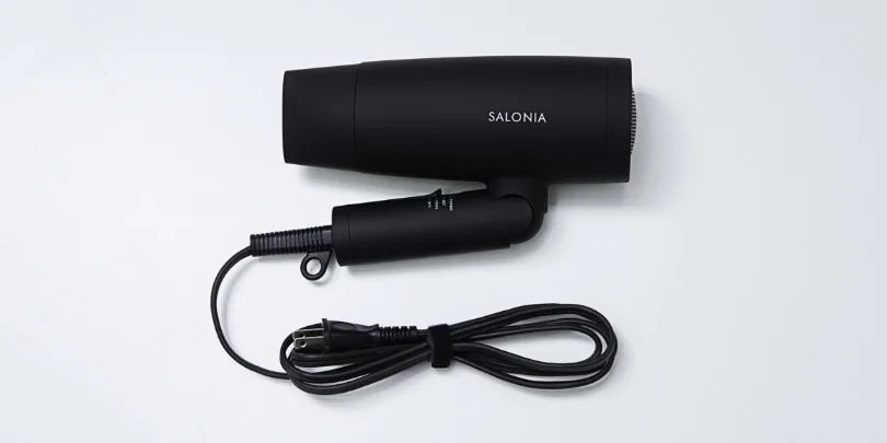 ハンドルを折りたたんだ状態のブラックのSALONIAスピーディーイオンドライヤーと電源コードを写した、SALONIA公式の画像