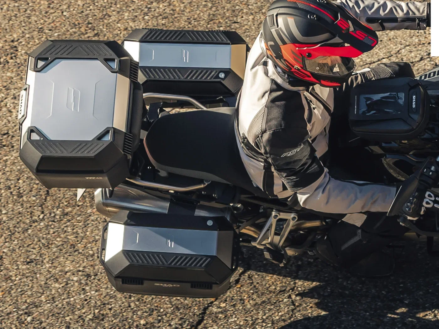 銀色のアルミパネルを備えたTR27サイドケースとTERRAのトップケースを装着したバイクに、ヘルメット姿のライダーがまたがる様子を真上から写したSHAD公式の画像