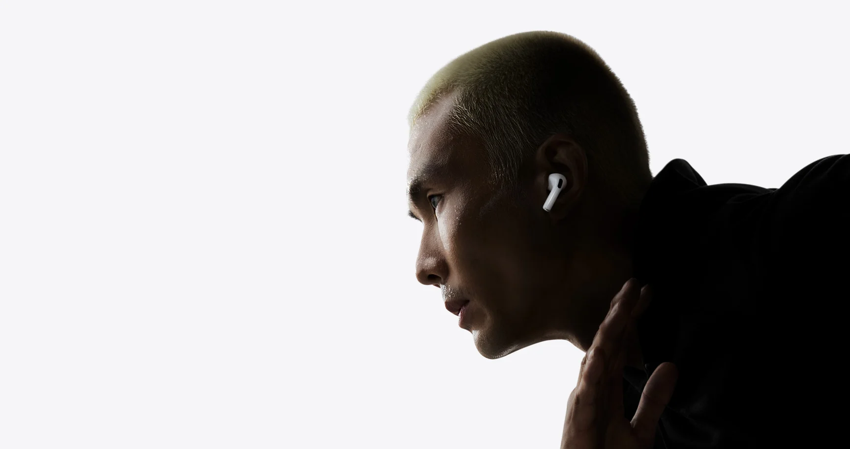 白い背景の前で前かがみの姿勢をとり、AirPods Pro 3を装着した男性を横から写したApple公式の画像