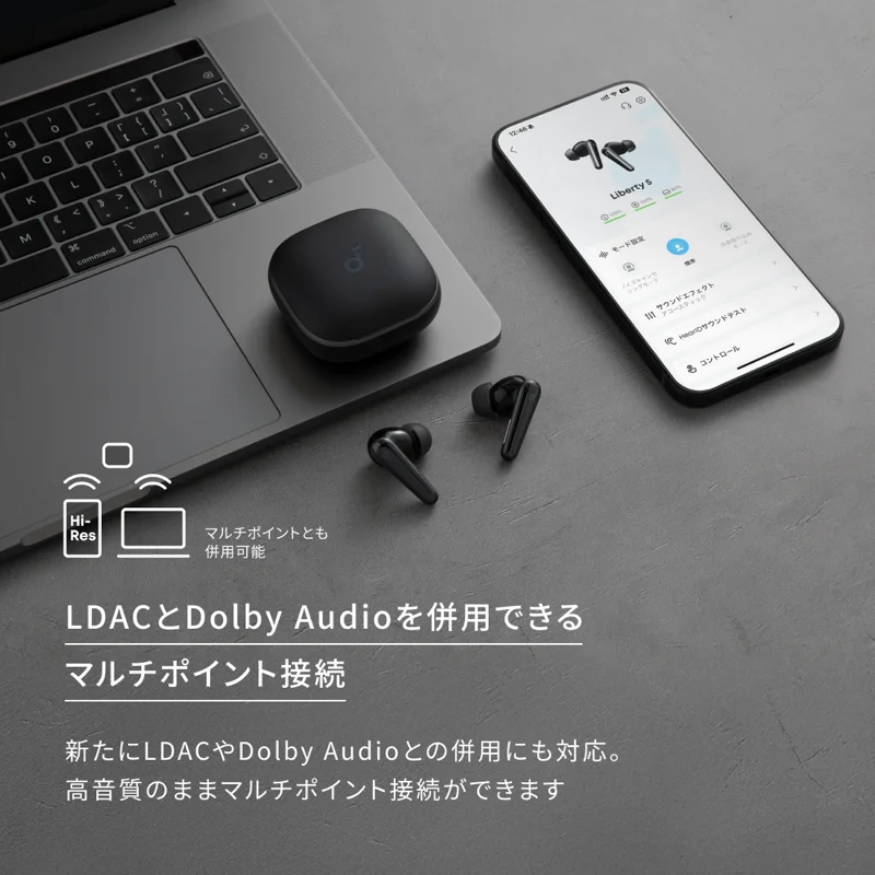 ノートパソコンの上の充電ケースとスマートフォンのSoundcoreアプリ画面を写した、マルチポイント接続を紹介するAnker公式の画像